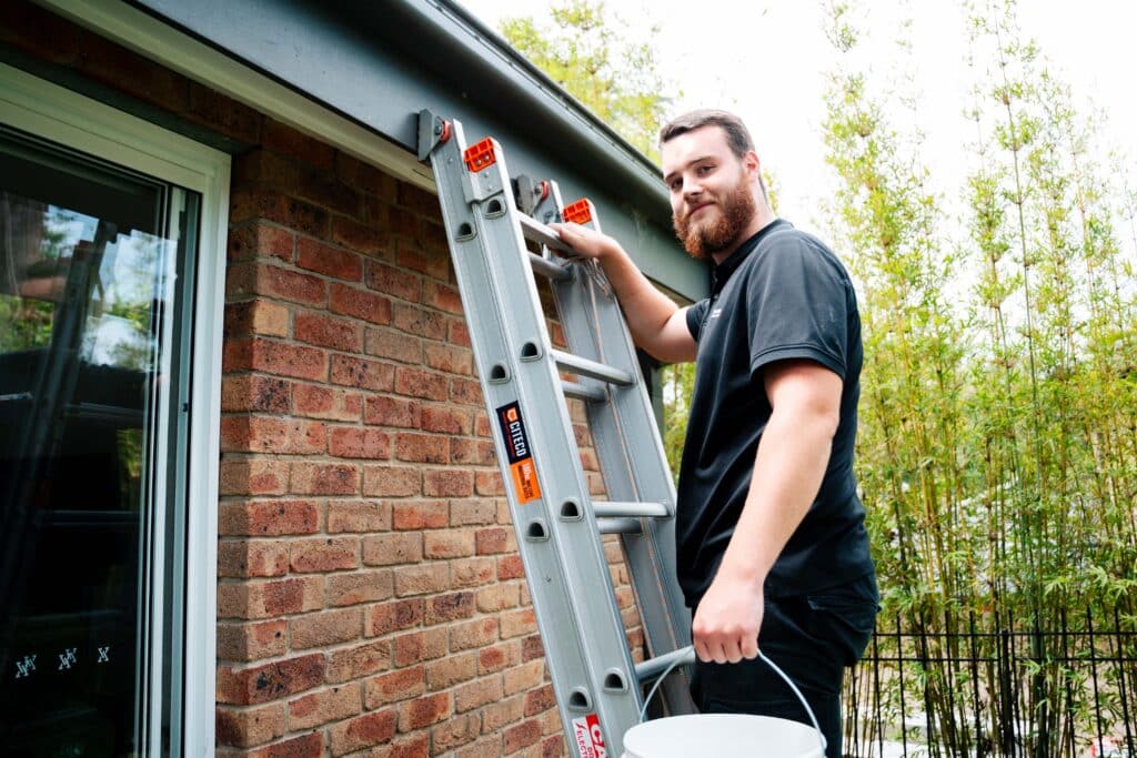 Plumber carrying ladder at residential property