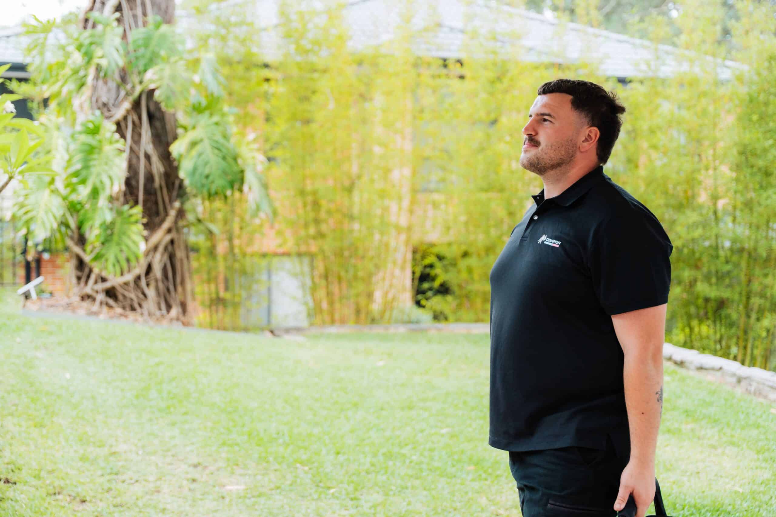 Champion Plumbing and Drains technician in branded uniform assessing a residential property exterior